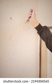 Older Man Removing Old Wallpapers Off The Walls In Empty Apartment