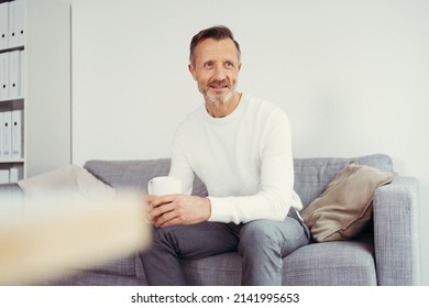 Older Man Sitting At Home On Sofa And Looking To The Side