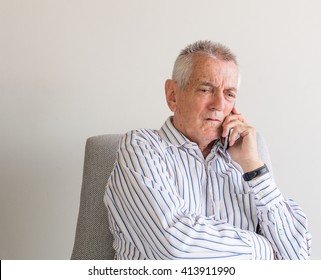 Older Man In Striped Shirt Talking On Mobile Phone And Looking Concerned