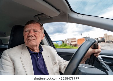 An older man in a suit sits in the driver's seat, gazing thoughtfully out the window at a developing industrial setting on a cloudy day - Powered by Shutterstock