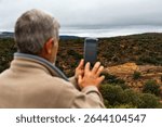 An older man takes a photo of the archaeological site of the Iberian settlement of Los Morrones, in Cortes de Arenoso, Castellón, Spain.
