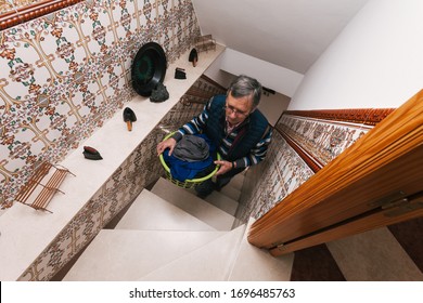 Older Man Taking Clothes Up To The Terrace Up The Stairs To Hang Them After Doing The Laundry. Homework. Househusband. Selective Focus.