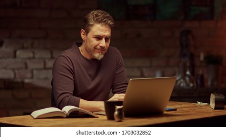 Older Man Tele Working With Laptop Computer At Home Office In Dark Room, Thinking, Looking Busy.