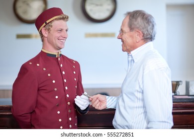 Older Man Tipping Bellhop In Lobby