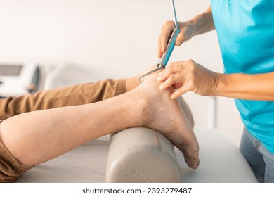 An older man is treated in a physiotherapy clinic with a hook and diacutaneous fibrolysis technique in the foot and ankle area - Powered by Shutterstock