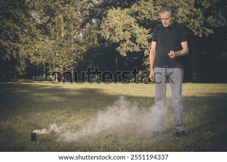 Older man uses two types of smoke machine generators on outdoor location
