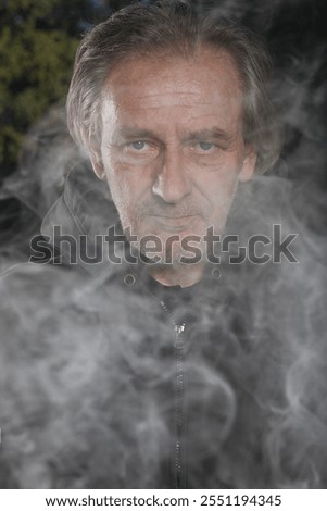 Older man uses two types of smoke machine generators on outdoor location