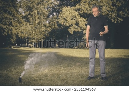 Older man uses two types of smoke machine generators on outdoor location