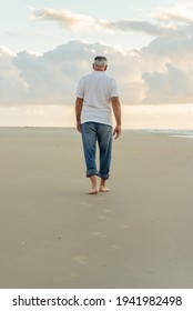 Older Man Walking Barefoot On The Beach