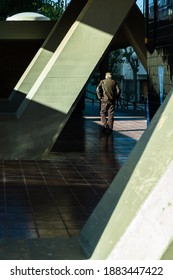 Older Man Walking Between Building Columns