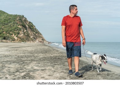 Older Man Walking A Dog In The Morning At The Beach