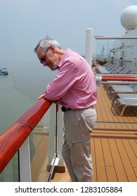 Older Man, Wearing Sunglasses Standing At The Railing Of Cruise Ship