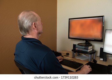 Older Man Who Needs A Haircut Sequesters At Home As He Works On The Computer.