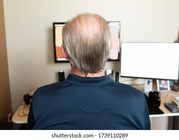 Older Man Who Needs A Haircut Sequesters At Home As He Works On The Computer.