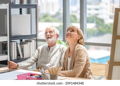 Older Man And Woman Drawing Together On A Canvas At Art Studio, Portrait Of Senior Couple Painting On A Canvas In Living Room, Happy Retirement Concepts