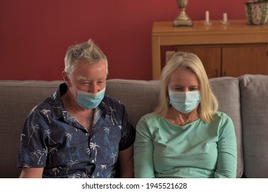 An Older Man And Woman Wearing Masks Sit Together On A Sofa With A Laptop In Front Of Them Talking To Family On A Video Call