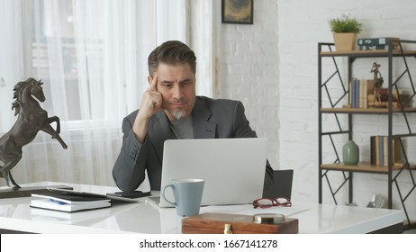 Older Man Working With Laptop Computer At Home Office, Thinking, Looking Busy.