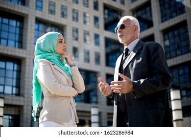 An Older Man And A Young Muslim Woman Are Talking About Work