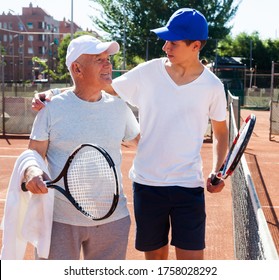 Older Man And Young Man Talking On Court Playing Tennis