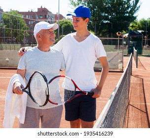 Older Man And Young Man Talking On Court Playing Tennis