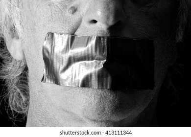 An Older Man's Mouth Is Covered And Taped Closed With Duct Tape, Side Lit With Half Of Face In Shadow, Finished In Black And White.