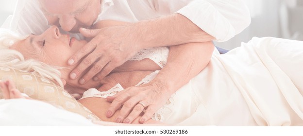 Older Marriage Kissing In Bed With Elderly Man Bending Over His Wife And Touching Her Face