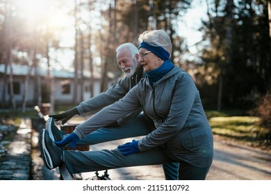 An Older Married Couple Enjoys Exercising And Jogging On A Beautiful Sunny Winter Day.