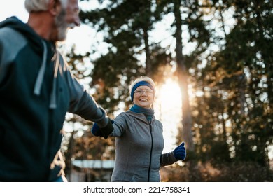 An Older Married Couple Jogging Together On A Beautiful Sunny Winter Day.