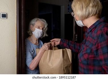 An Older Masked Woman Receives A Bag Of Food From Volunteer Neighborhood Help