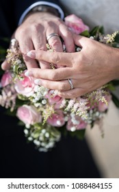 Older Mature Bride And Groom Hands And Rings On Wedding Bouquet Close Up