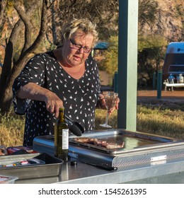 Older Mature Woman Cooking On A Barbeque At A Free Camping Area.