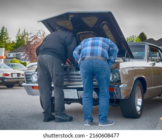 Older Men Admire Engine Of Vintage Car At Exhibition.