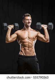 Older Muscular Bodybuilder Holding Dumbells Weights With Black Background