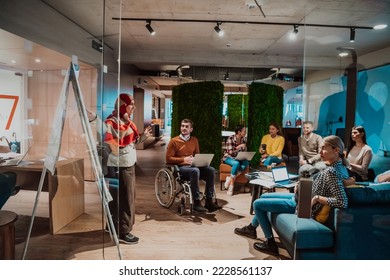 An older Muslim businesswoman presents a project to a young diverse team of people in a modern office - Shutterstock ID 2228561137