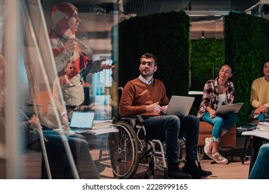 An older Muslim businesswoman presents a project to a young diverse team of people in a modern office - Shutterstock ID 2228999165