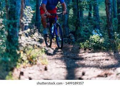 Older Overweight Man Rides A Mountain Bike Through The Woods Using Extreme Effort.