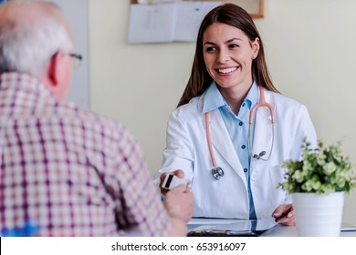 Older Patient At Woman Doctor Office Paying Exam With Credit Card