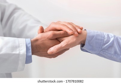 Older people healthcare support concept. Doctor holding hand of senior woman at medical visit, close up