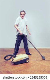 Older Poor Man Cleaning His Home With Vacuum Cleaner