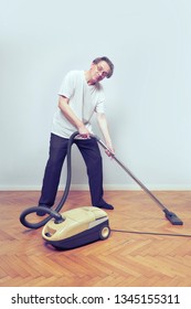 Older Poor Man Cleaning His Home With Vacuum Cleaner