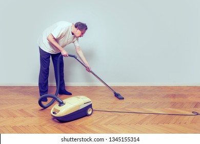 Older Poor Man Cleaning His Home With Vacuum Cleaner