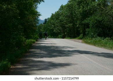 Older Retired Couple Hiking Down A Mountain Road