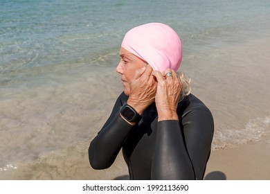 Older Retired Woman In Wetsuit Putting On Swimming Cap