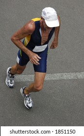 An Older Runner In A Triathlon Race, Taken From Above. Motion Blur On His Feet.