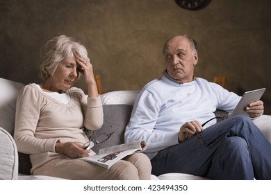 Older sad woman with headache sitting next to her senior worried husband - Shutterstock ID 423494350