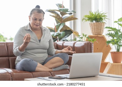 An Older Senior Grey Hair Asian Woman Sitting On Sofa And Learn How To Do Yoga Training From Notebook Computer.