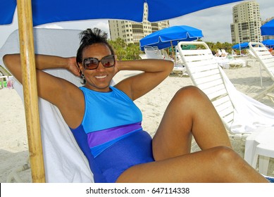 Older Senior Woman Relaxes In Chaise On Beach