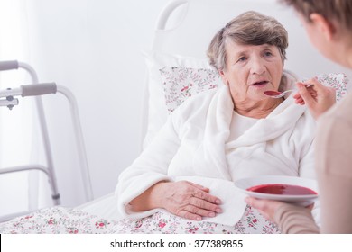 Older Sick Woman Eating Dinner With Caregiver's Help