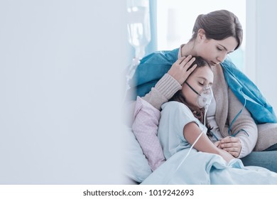 Older sister and girl in the hospital breathing using an oxygen mask