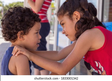 Older Sister Sculls Younger Brother By Getting In His Face And Putting Her Hands On His Shoulders. The Little Boy Is Clearly Upset With His Sister Outdoors In Public.